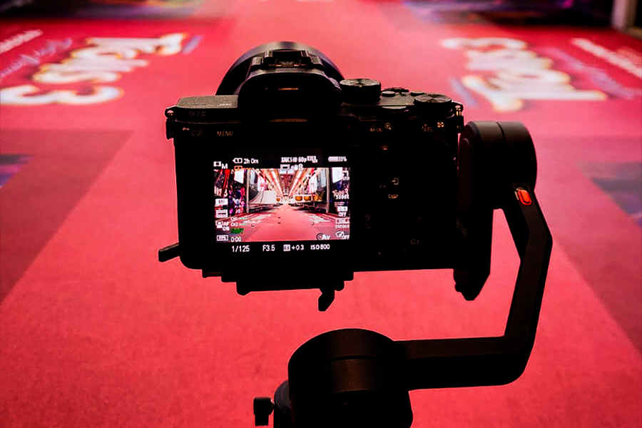 Uma câmera de vídeo em foco na imagem, ao fundo, um chão vermelho, gravando um video case