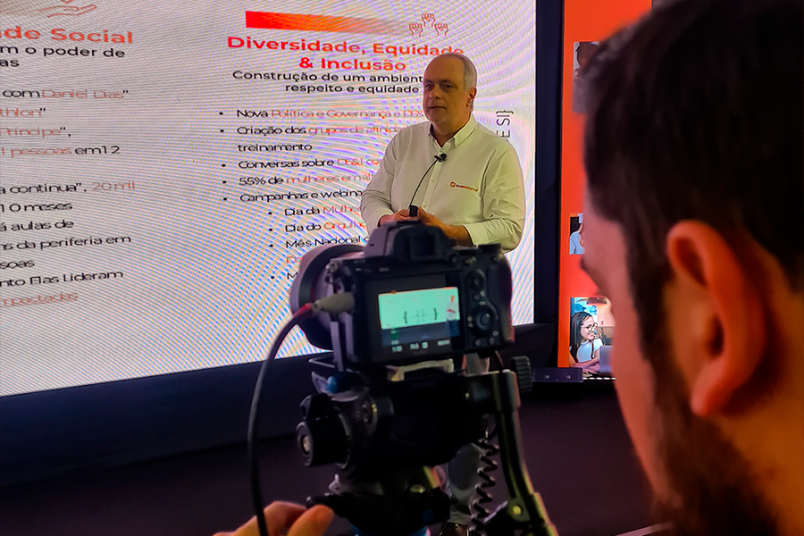 Homem com câmera de video, de uma produtora de vídeo em São Paulo, gravando apresentação de slide de um homem a sua frente