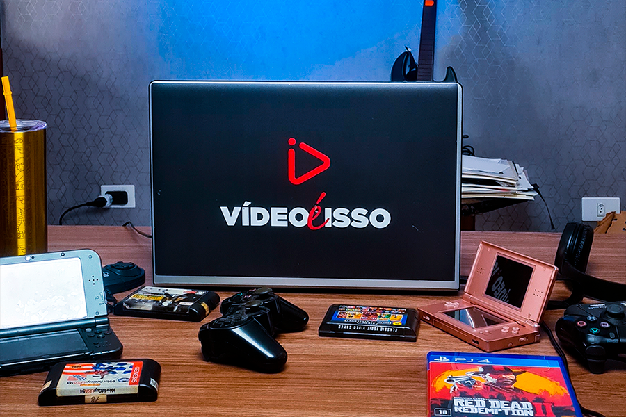 notebook com adesivo da vídeo é isso, sobre a mesa, com vários videogames 